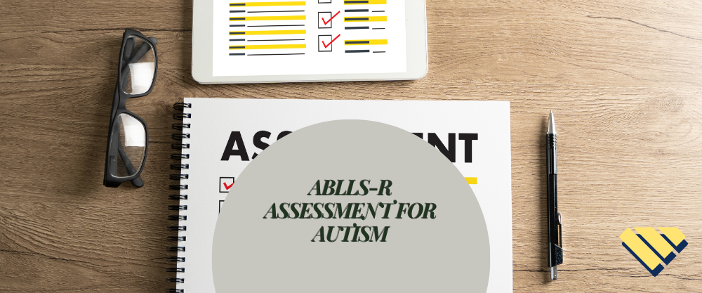 ABLLS-R Assessment for Autism graphic displayed over an assessment checklist on a wooden desk with glasses, pen and tablet.